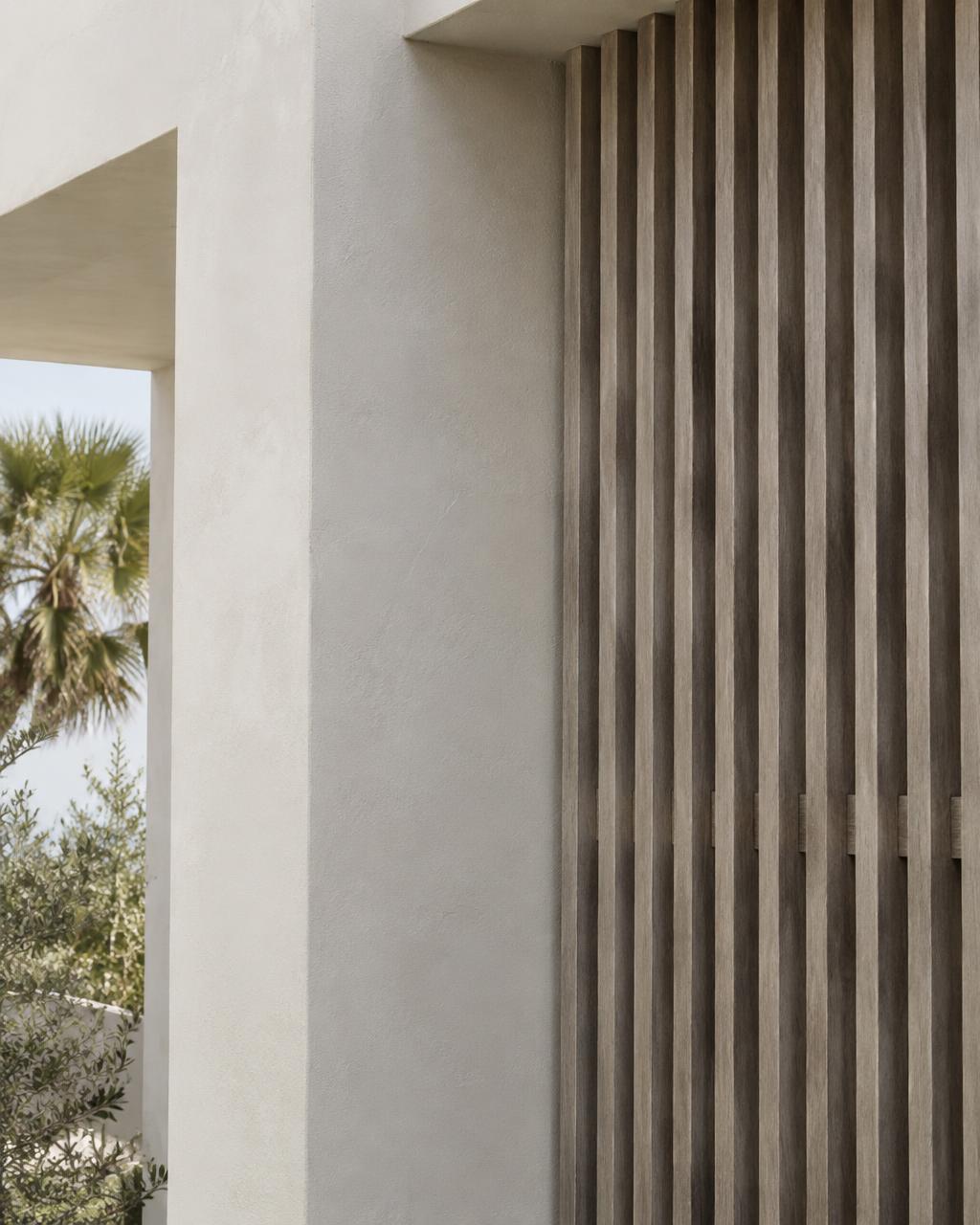 Stucco wall meeting vertical timber louvers on a coastal residence